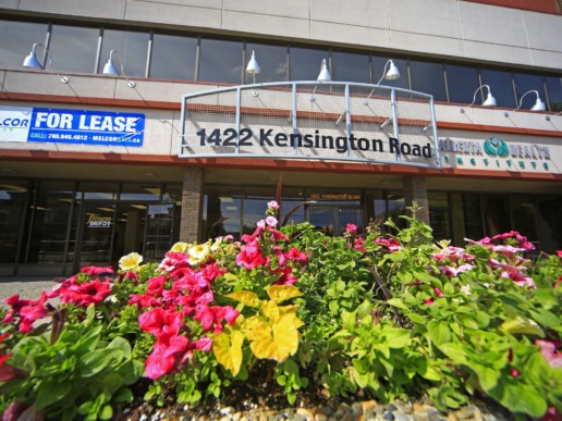 Bright flower container gardens line the entrance to 1422 Kensington Road, for lease by Melcor REIT.